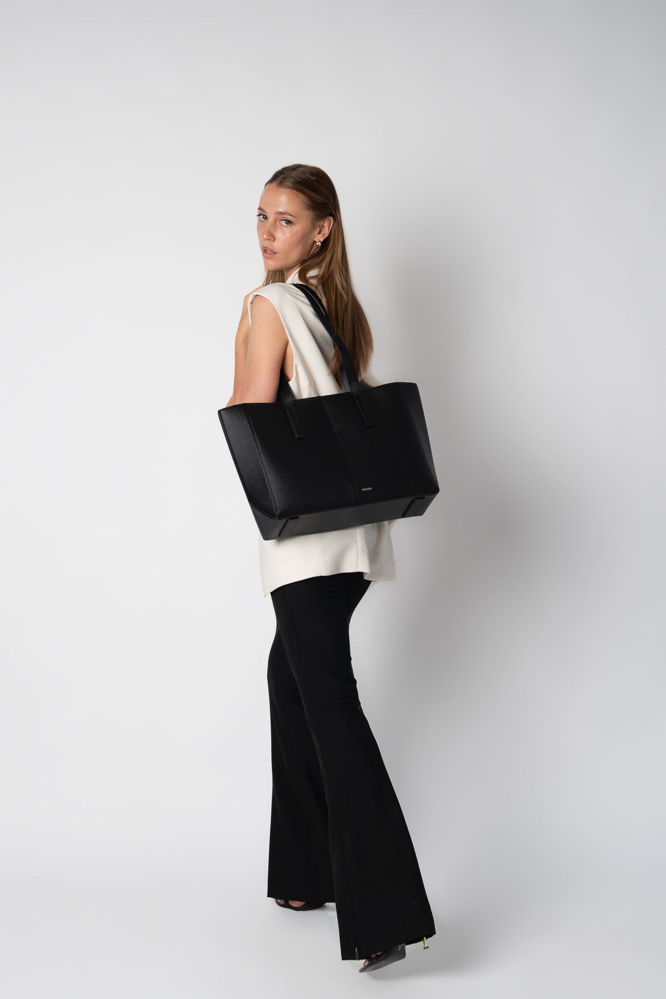Model holding black daely tote from behind