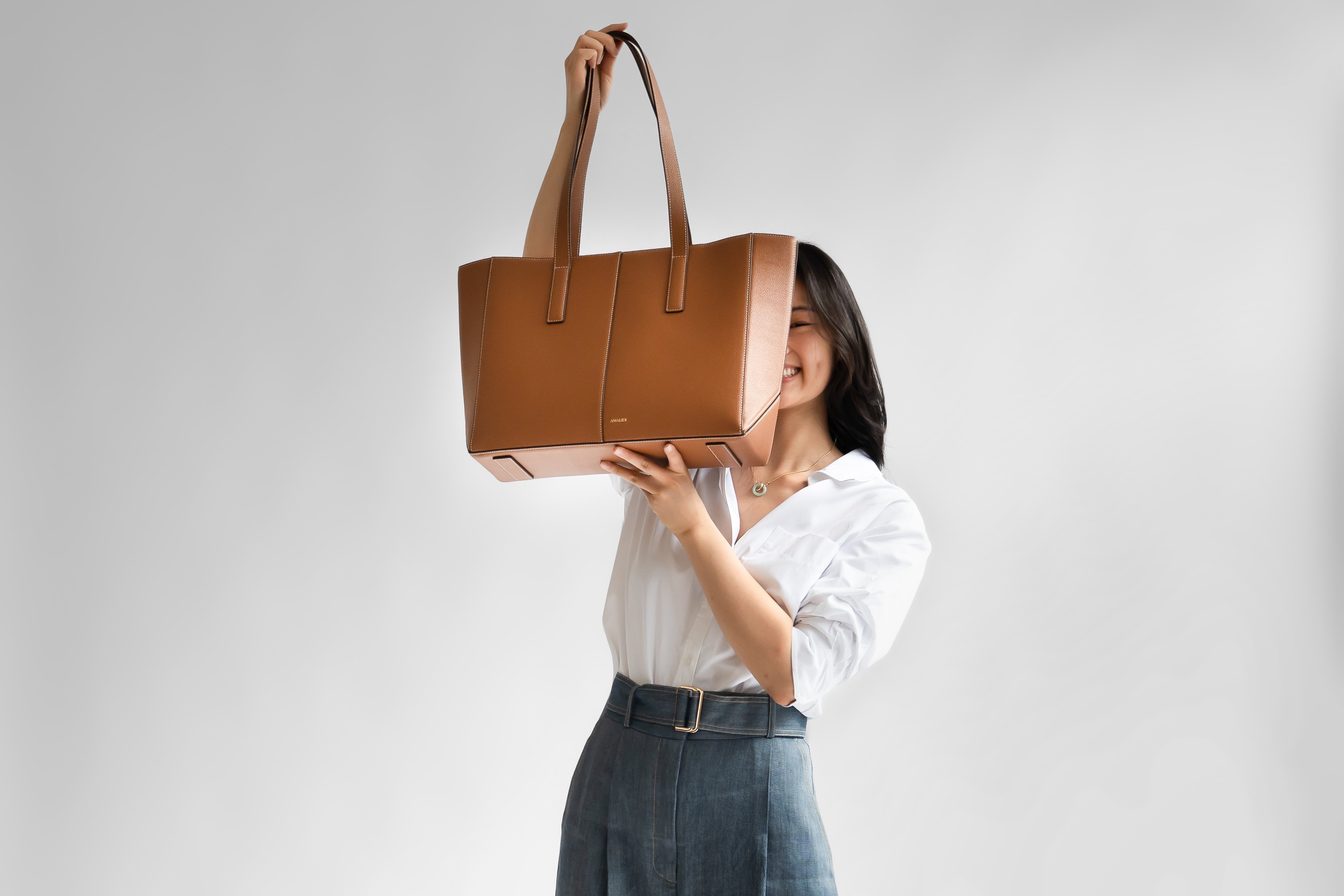 Model covering half her face with the camel daely tote
