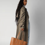 Model holding camel daely tote in fall outfit