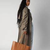 Model holding camel daely tote in fall outfit