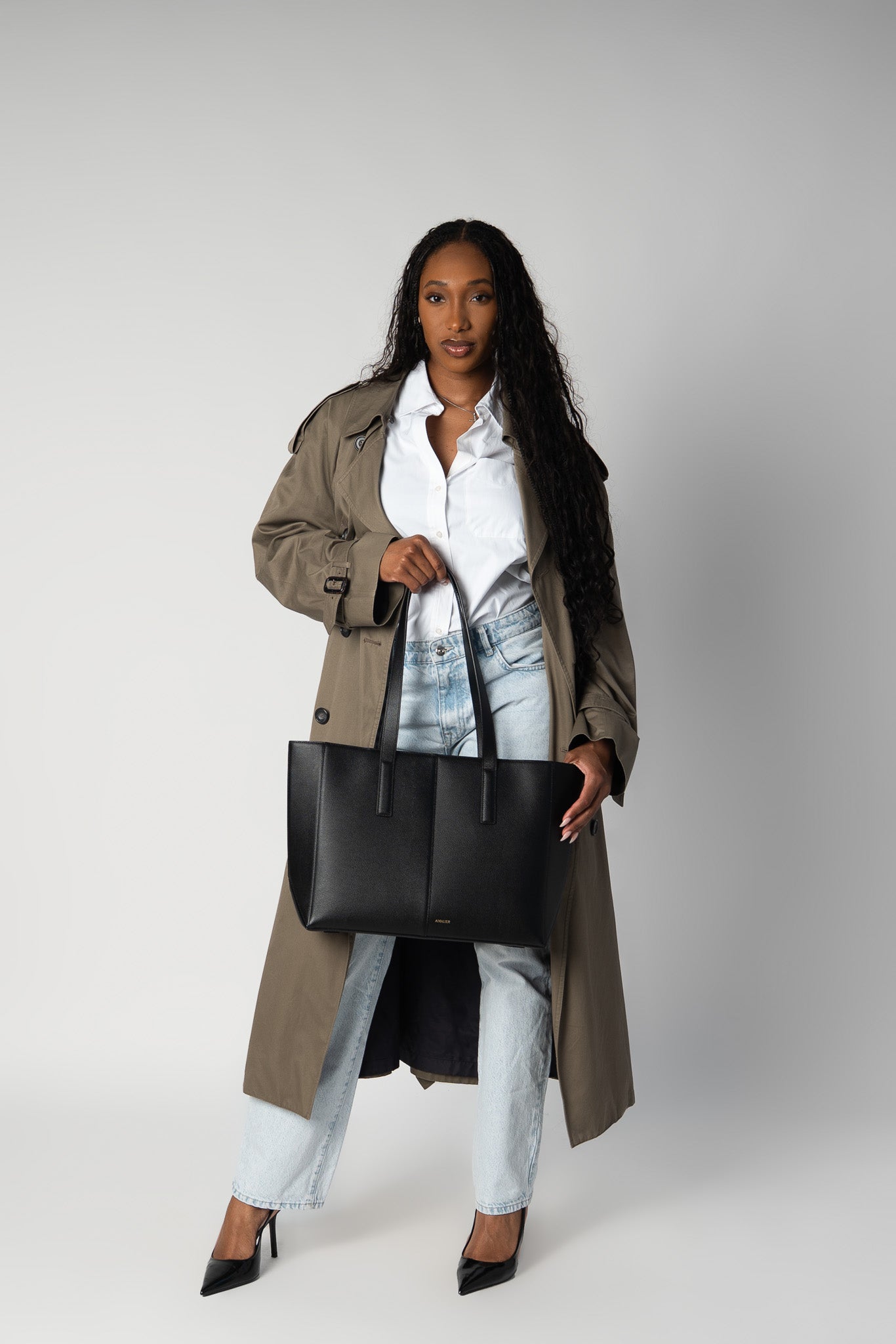 Model holding the black daely tote in fall-themed outfit