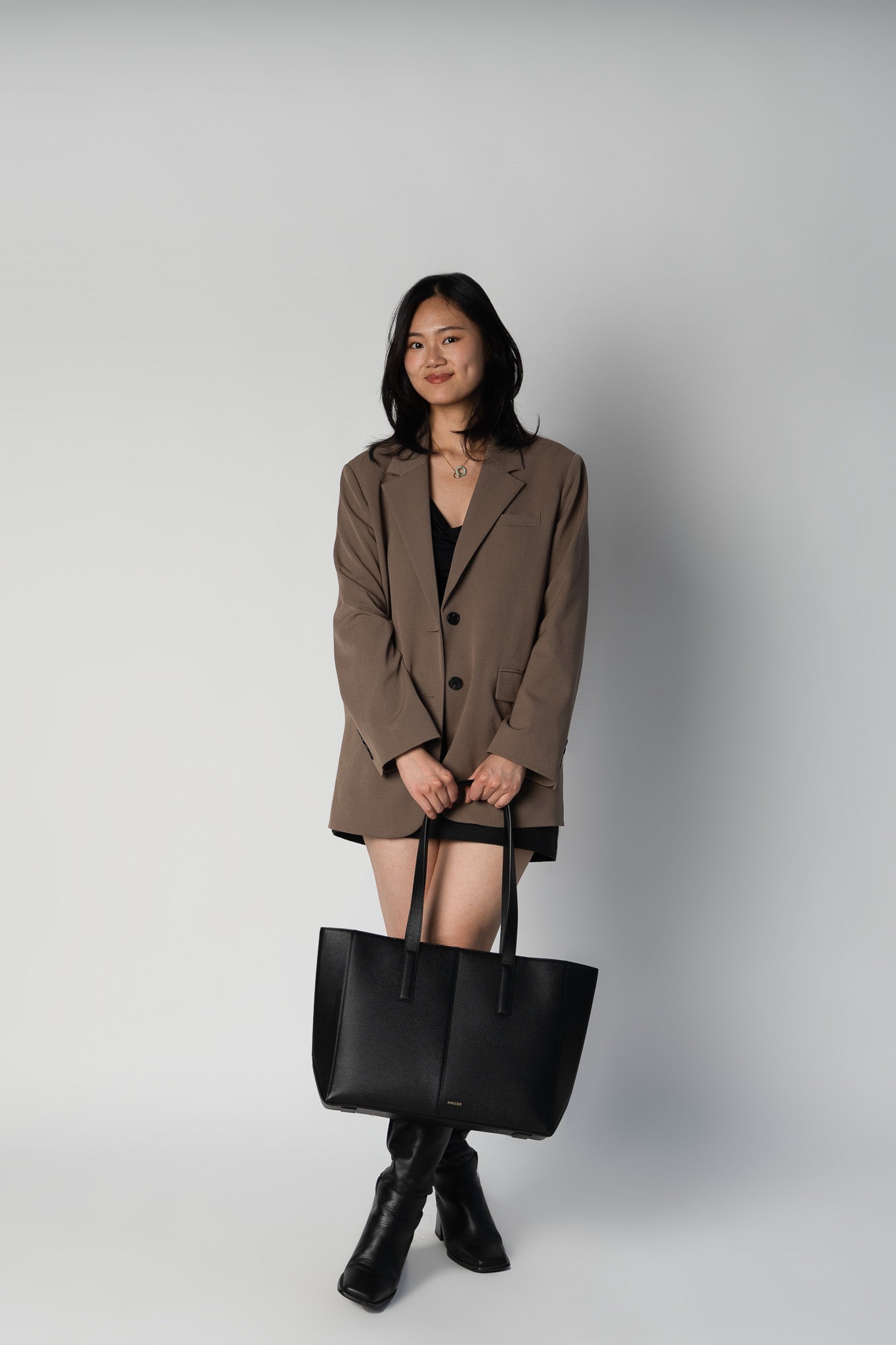 Model holding black daely tote in business casual outfit
