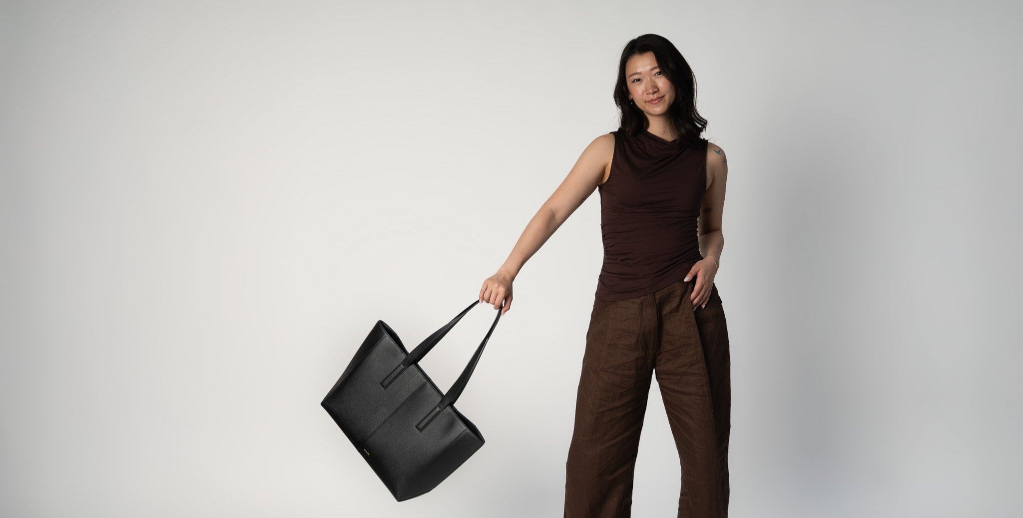 Model swinging the black daely tote