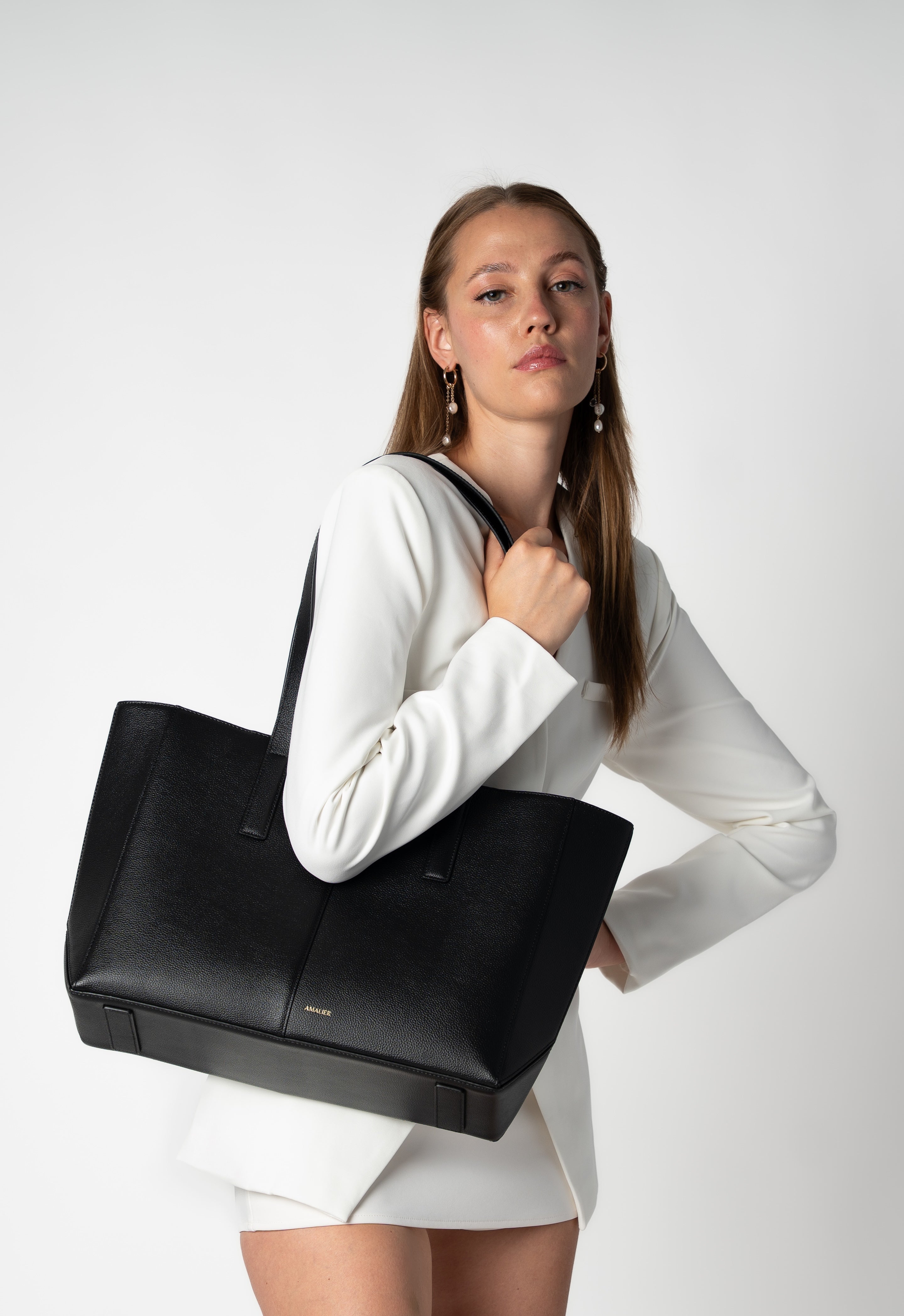 Model holding black daely tote in business casual outfit